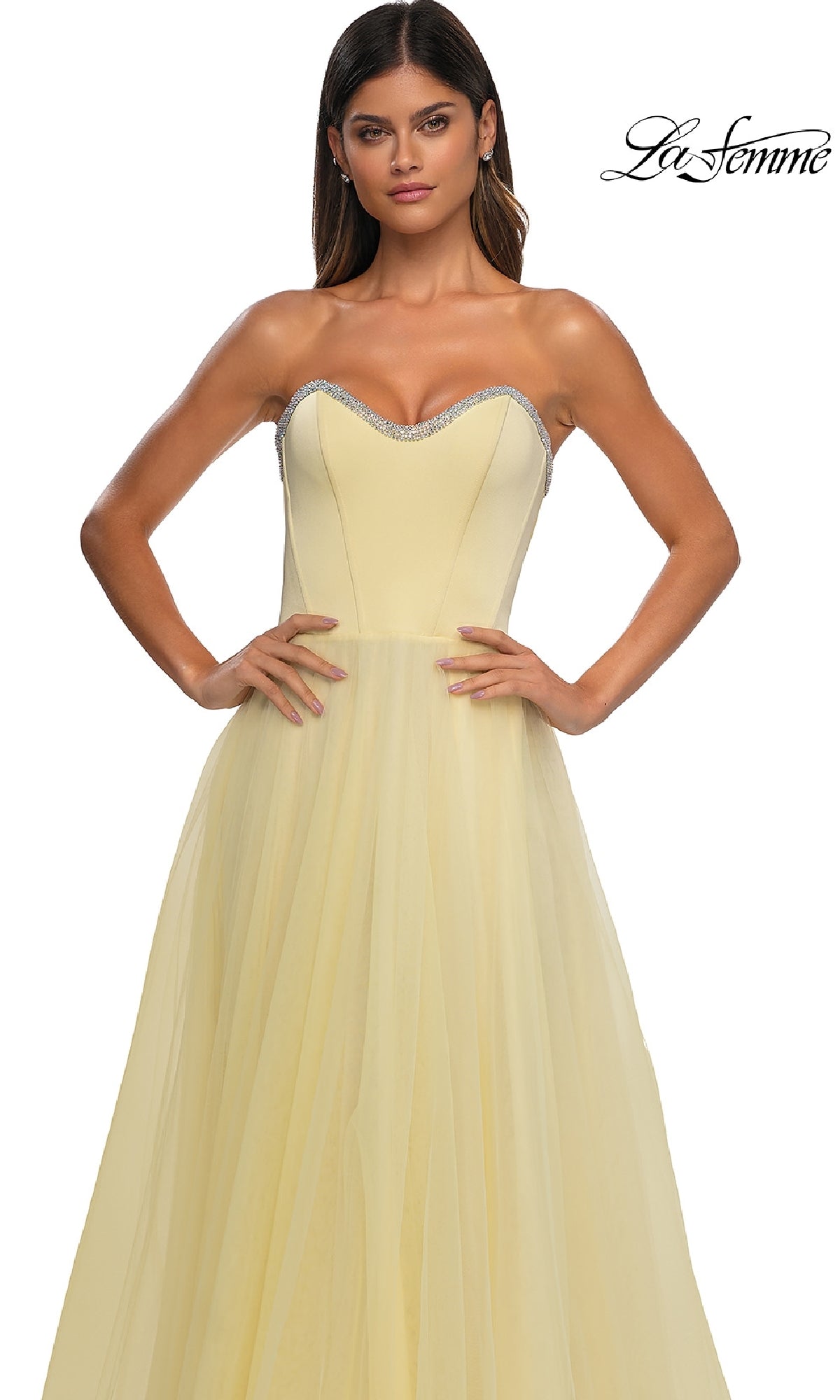 A woman wears the La Femme 32731 Strapless Long Prom Ball Gown in light yellow, featuring a fitted bodice, tulle skirt, silver-trimmed sweetheart neckline, and the